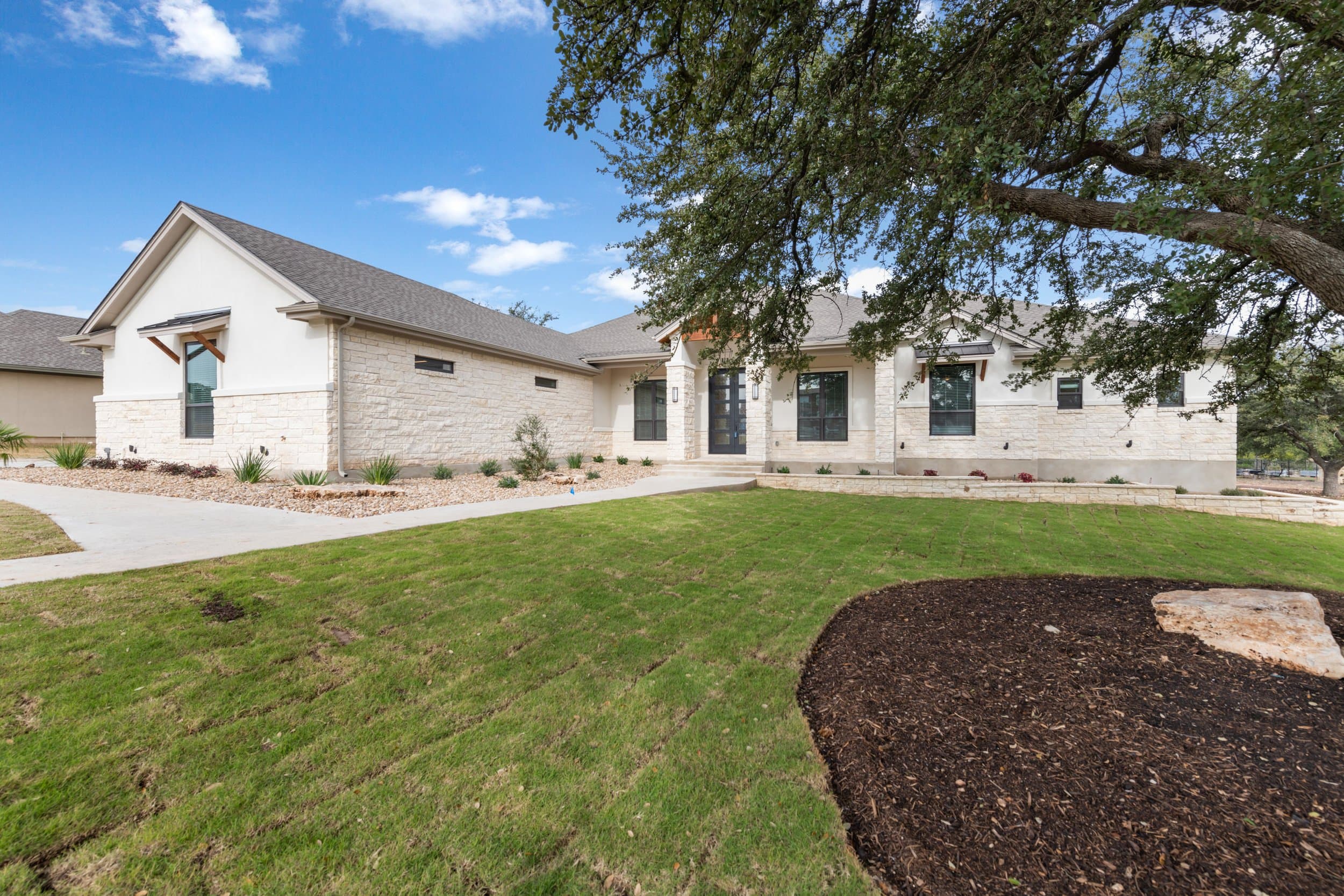 Single-story limestone custom home under a live oak